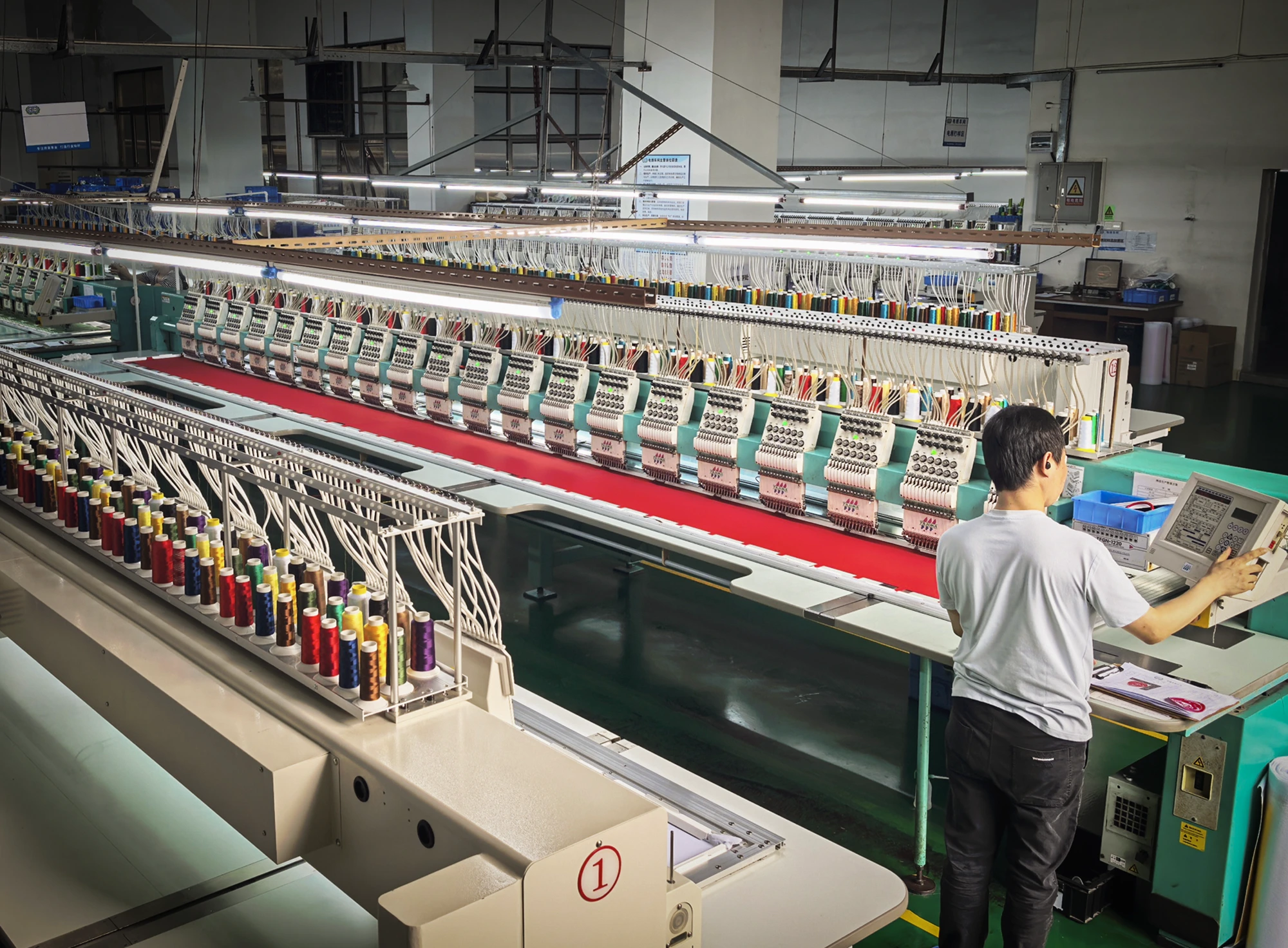 Large embroidery production line with operator producing custom badges and patches in a controlled factory environment